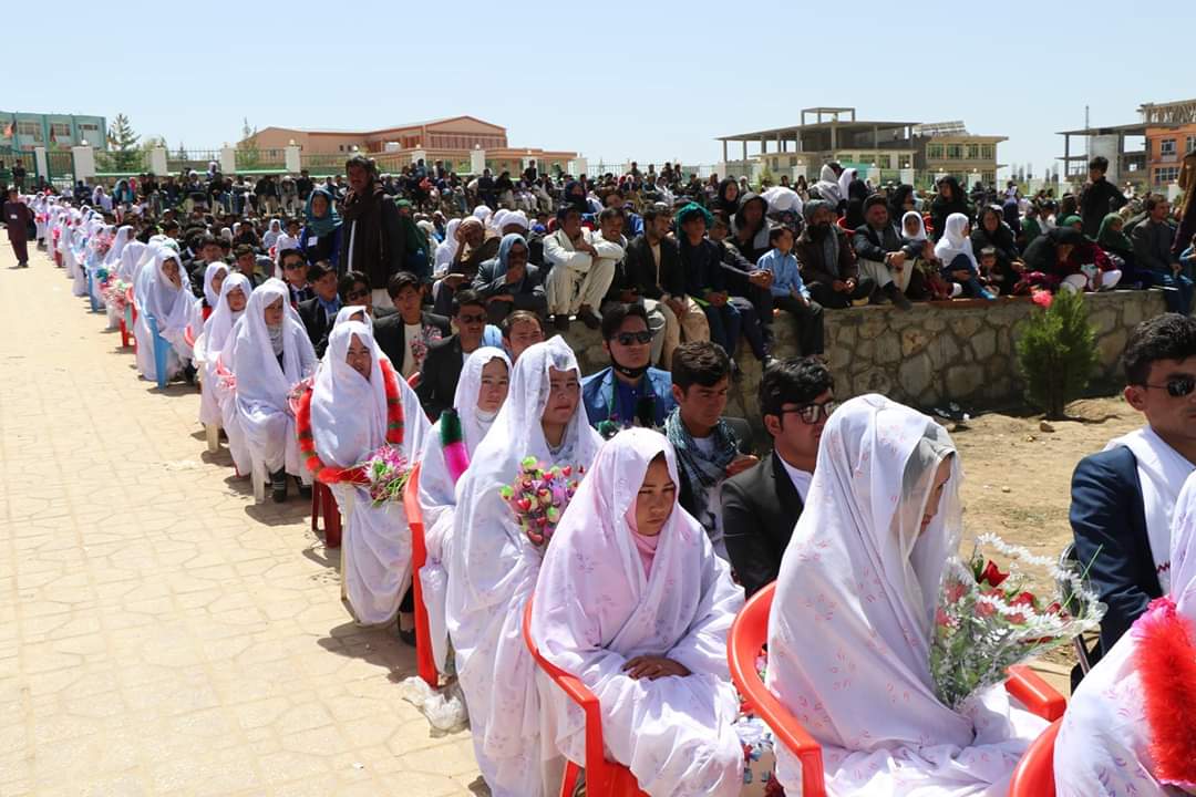A mass wedding ceremony with a hundred young couples and an audience seated in the background