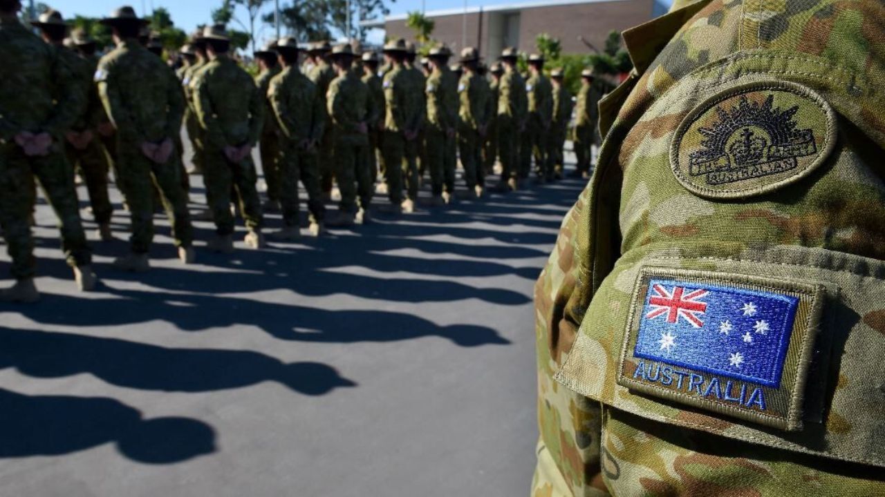 Australian soldiers standing in line with the national insignia and unit badge.
