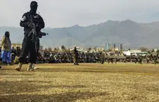 عضو مسلح پولیس و تجمع باشنده گان در یک میدان ورزشی