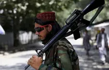 مردی با کلاه قرمز و اسلحه سنگین روی شانه در خیابان