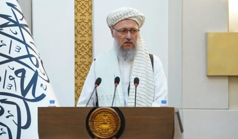 عبدالسلام حنفی با دستار سفید و عینک پشت تریبون سخنرانی