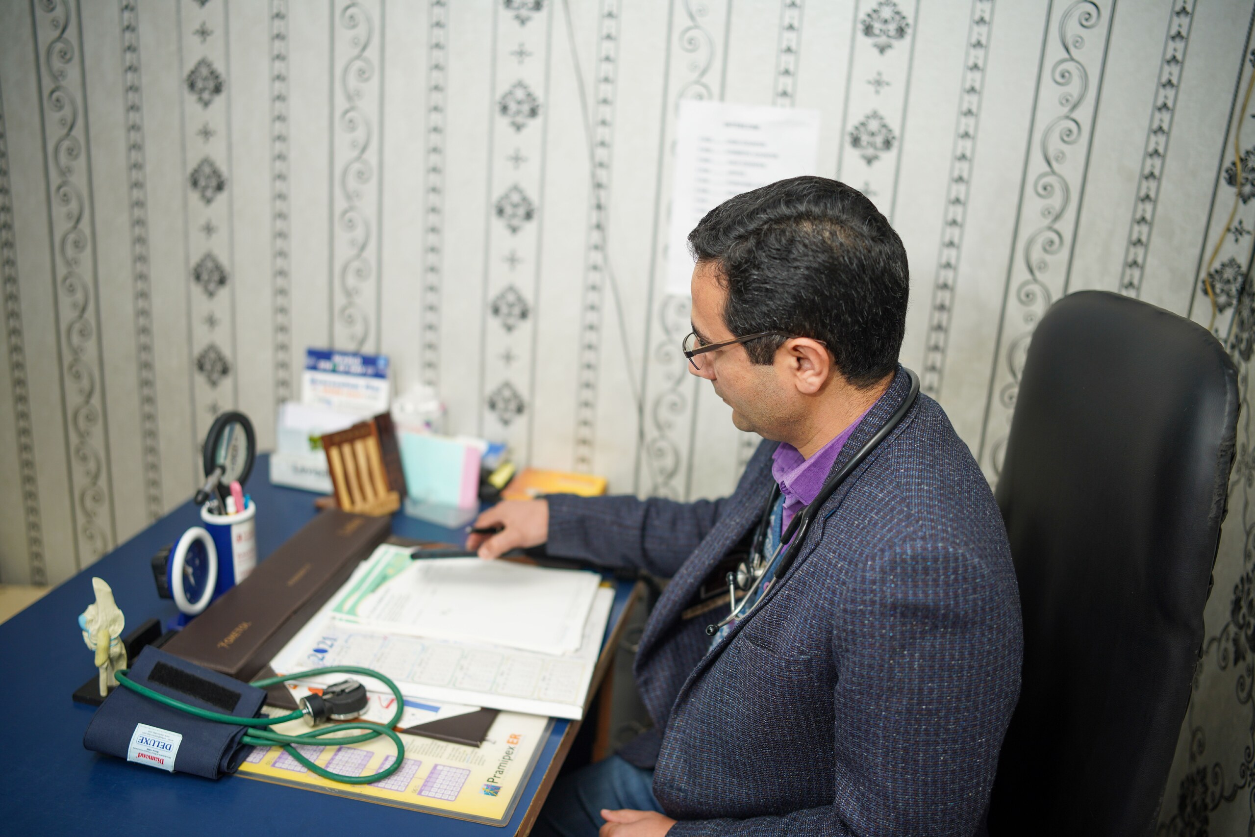 Doctor reviewing medical documents at his desk in the clinic office