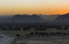 منظره غروب خورشید بر شهر کابل و کوه‌های پس‌زمینه با جاده و درختان در پیش‌زمینه